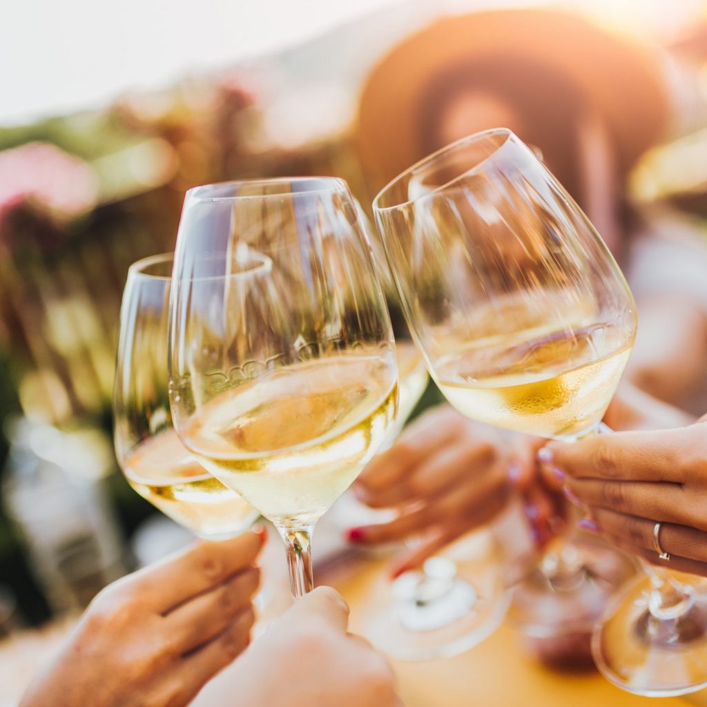People clinking glasses with wine on the summer terrace of cafe or restaurant